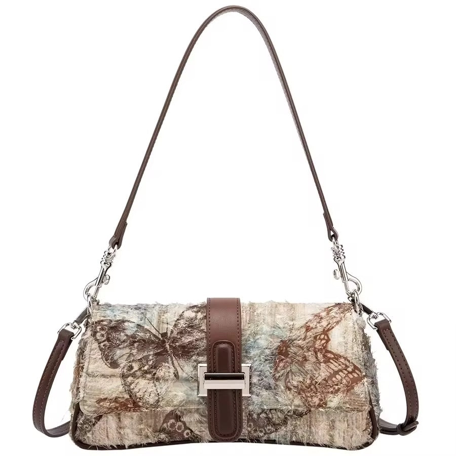 A multicolored handbag with a floral butterfly pattern and brown accents, featuring stainless steel hardware and a brown shoulder strap from Radiant Co Shop.